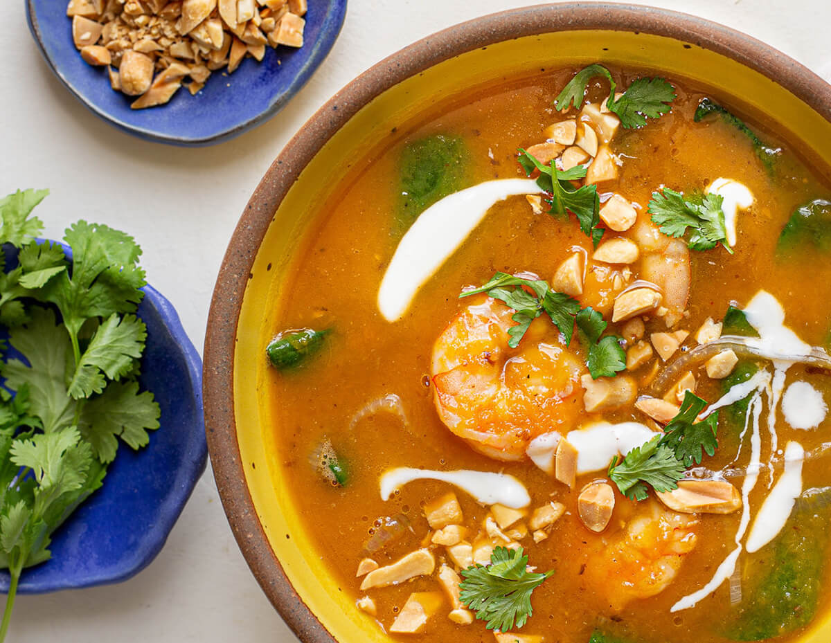 A bowl of butternut squash shrimp soup topped with crushed peanuts and cilantro