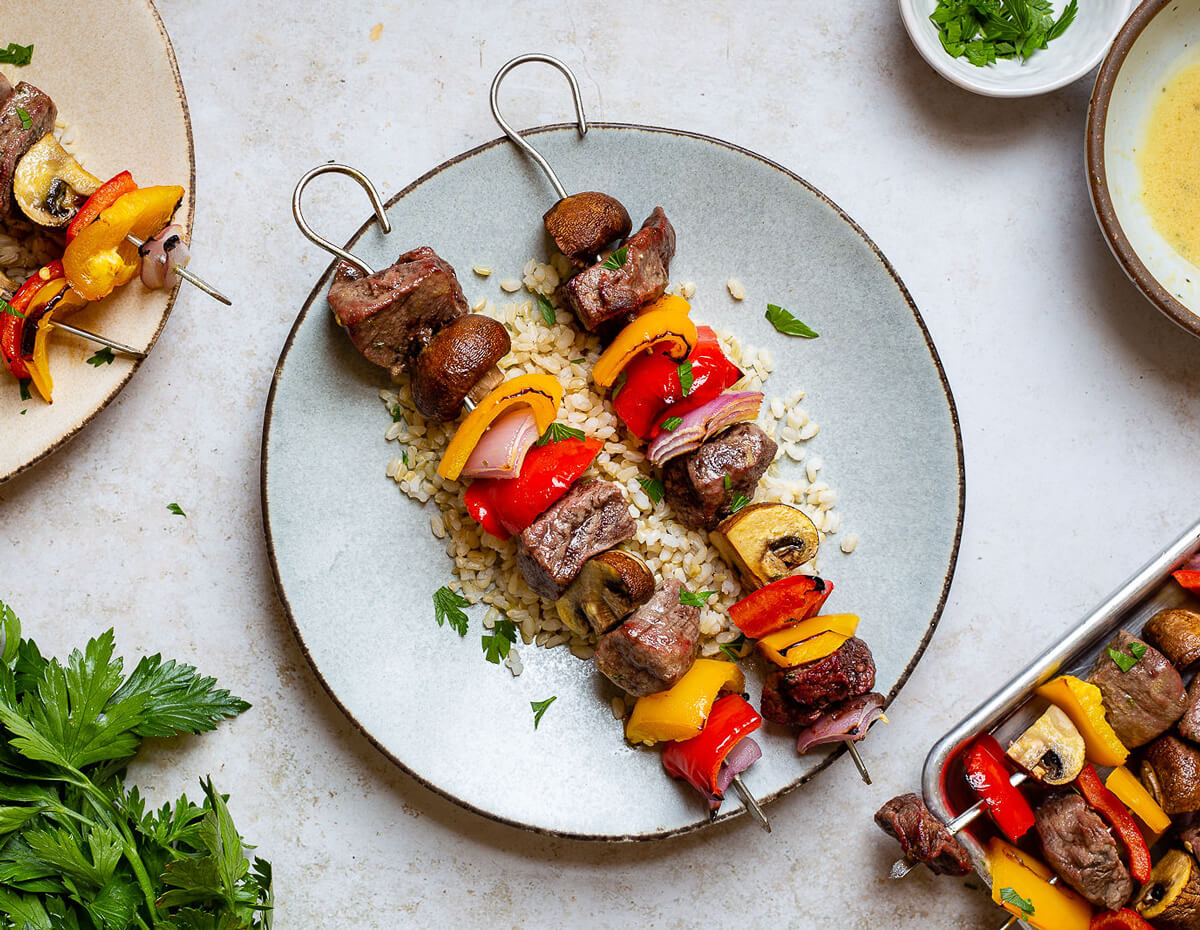 A serving of tasty beef kabobs on a plate over rice