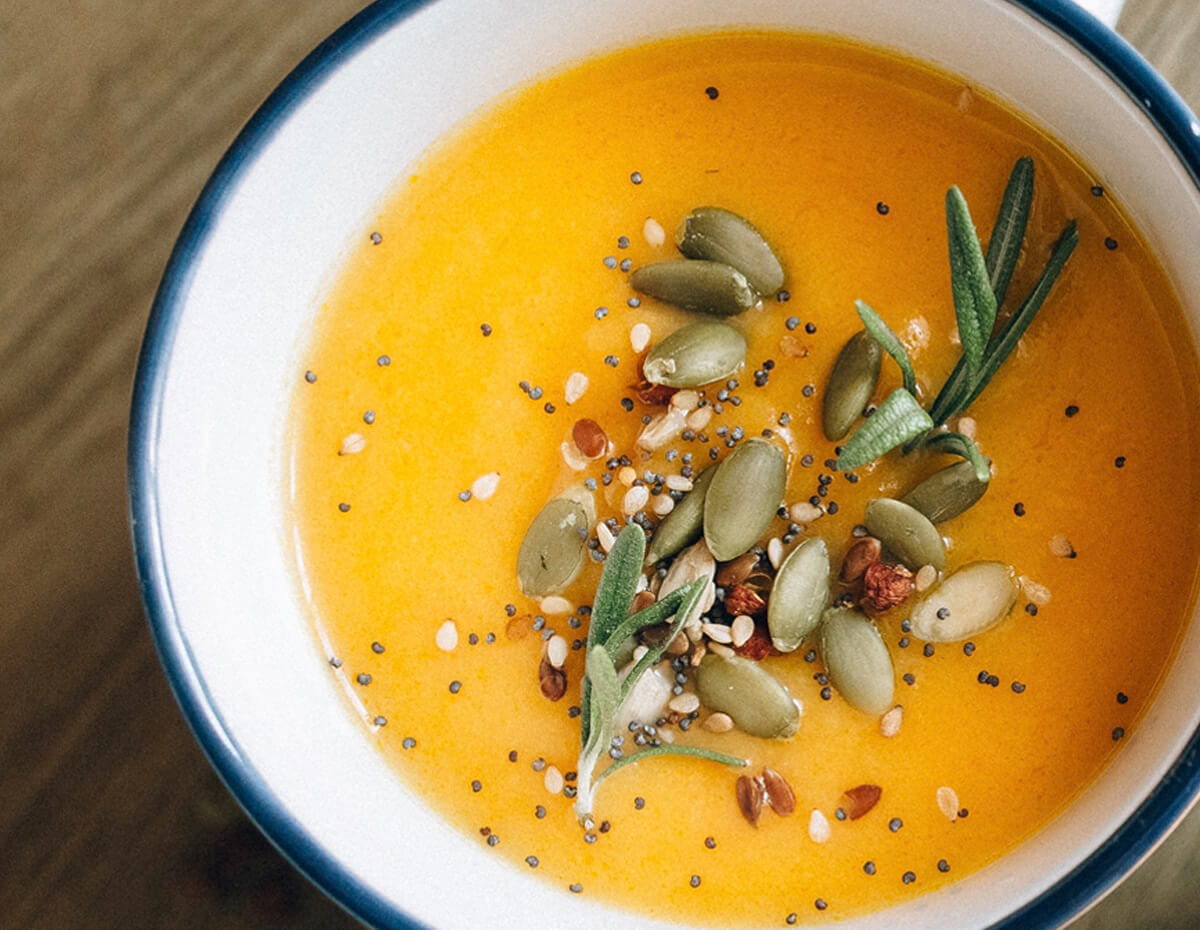 A bowl of butternut squash soup topped with rosemary and pumpkin seeds