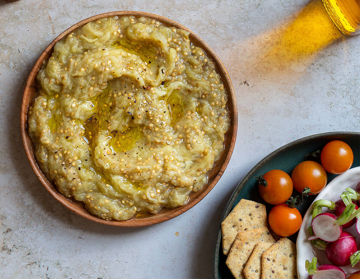 Some eggplant dip served along side cherry tomatoes, radishes and crackers