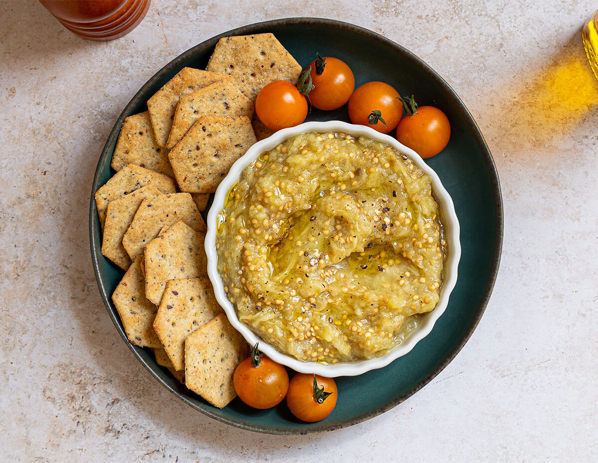 Some eggplant dip served along side cherry tomatoes and crackers