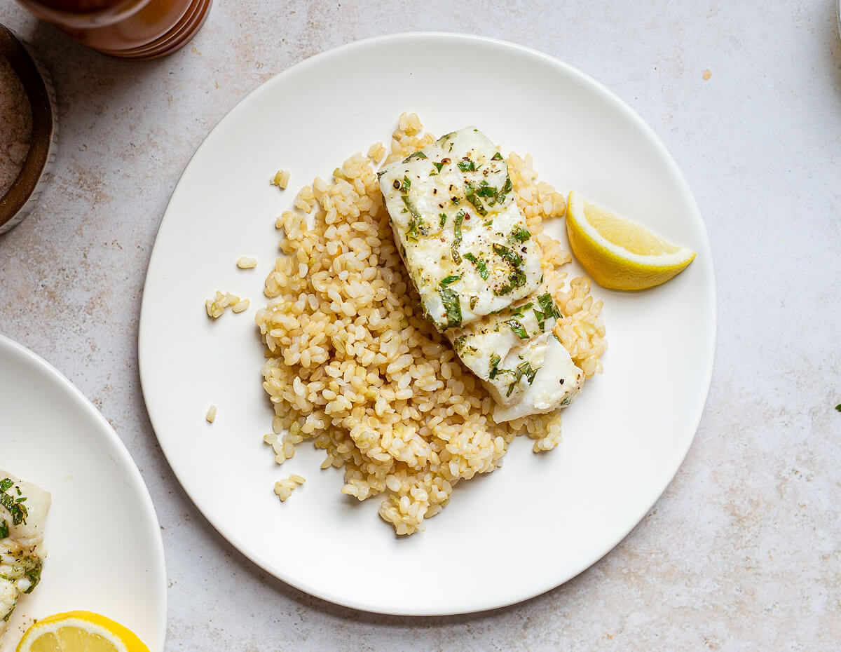 A fillet of roasted haddock served with lemons over rice